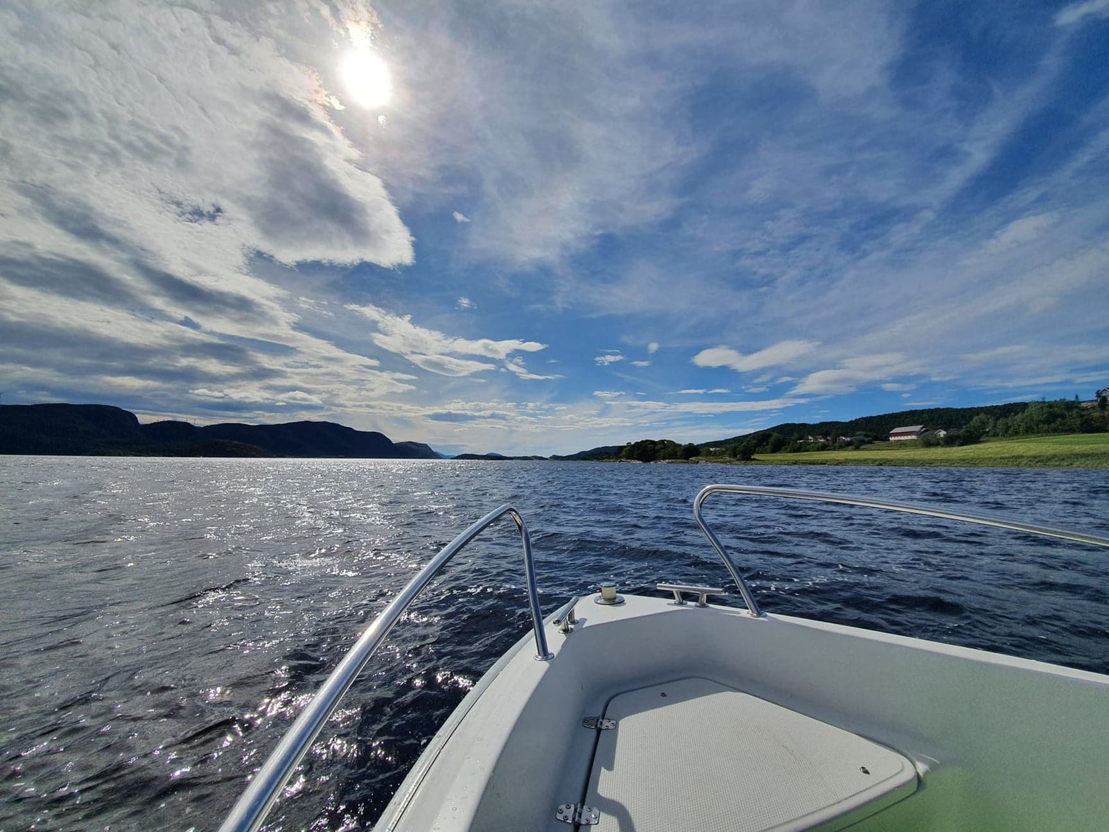 Båt på sjøen med blå himmel og sol